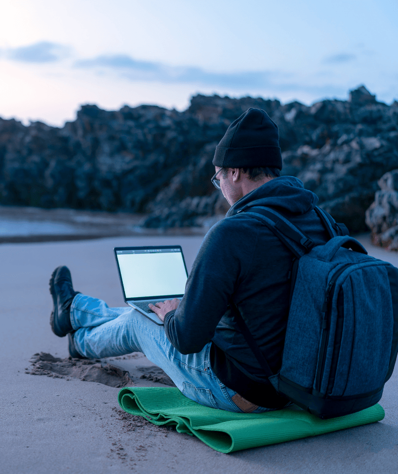 A person working on a laptop while sitting on a beach, illustrating remote work and a flexible nomadic lifestyle. 🏷️ Caption Work from anywhere — stay protected everywhere. 📄 Long Description The image shows an individual sitting on a beach with a laptop, dressed casually and surrounded by natural coastal scenery. The relaxed posture, outdoor setting, and portable workspace reflect the freedom and flexibility of the digital nomad lifestyle. This visual supports the theme of digital nomad insurance — comprehensive cover designed for people who work remotely, travel frequently, and live without fixed borders. 🔖 Image Title Remote work on the move If you want, I can help you unify all your Digital Nomad images into a consistent tone or craft a headline for the whole section.