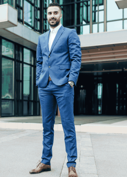 A confident professional standing outside a modern building, dressed in a blue suit, representing expertise and international-level service.